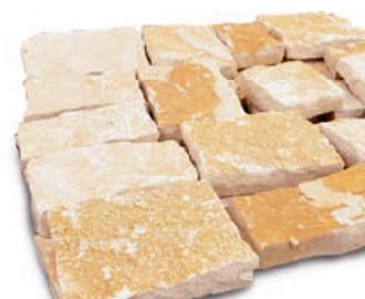 Plaquettes de parement en pierre calcaire jaune, posées à plat avant application.