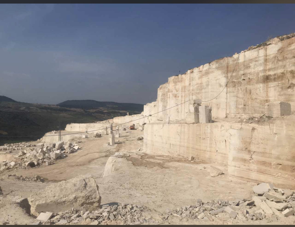 Front de carrière de travertin à ciel ouvert, blocs extraits au premier plan.