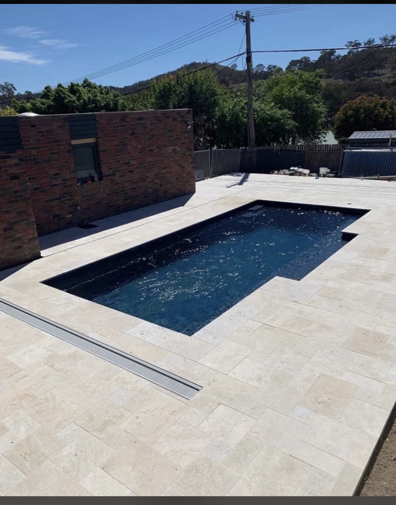 Pavé de travertin Light autour d'une piscine, teinte crème claire.